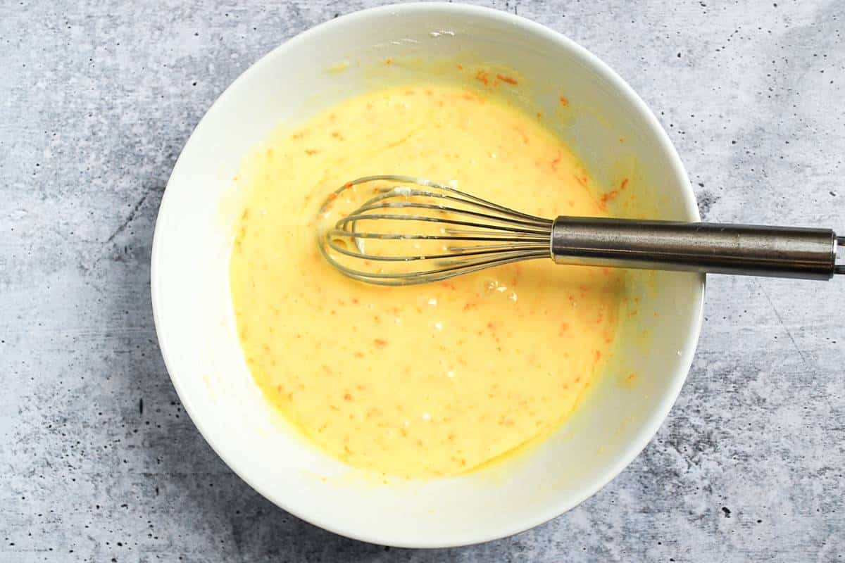orange cookie glaze in a bowl with a whisk