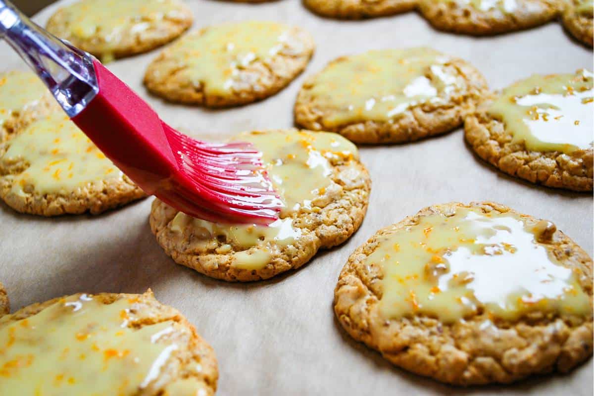 brushing orange cake mix cookies with a glaze