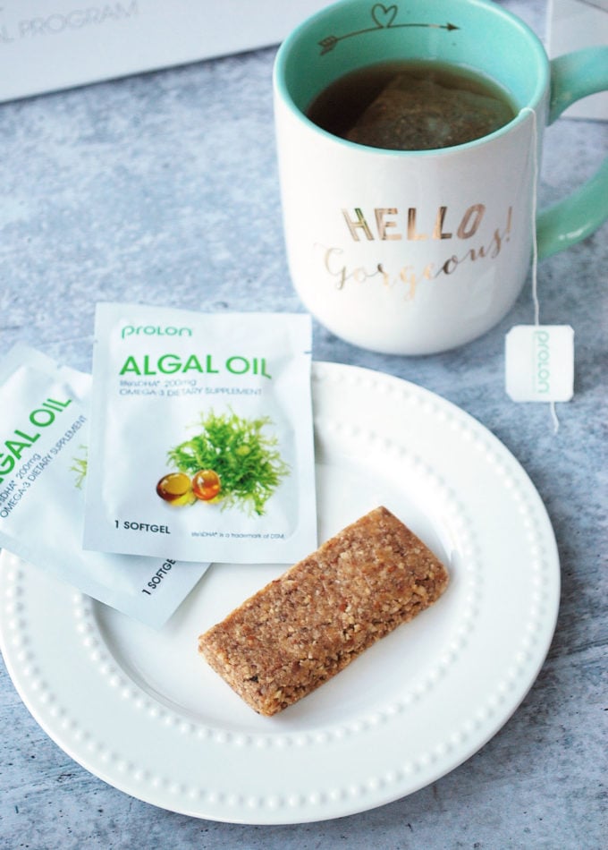 Fast bar on a plate with packaged supplements and a mug of tea