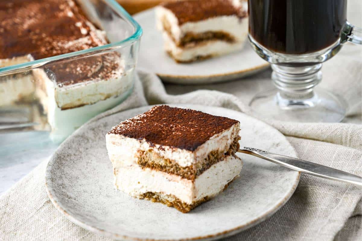 a serving of tiramisu dusted with cocoa on a plate with a fork