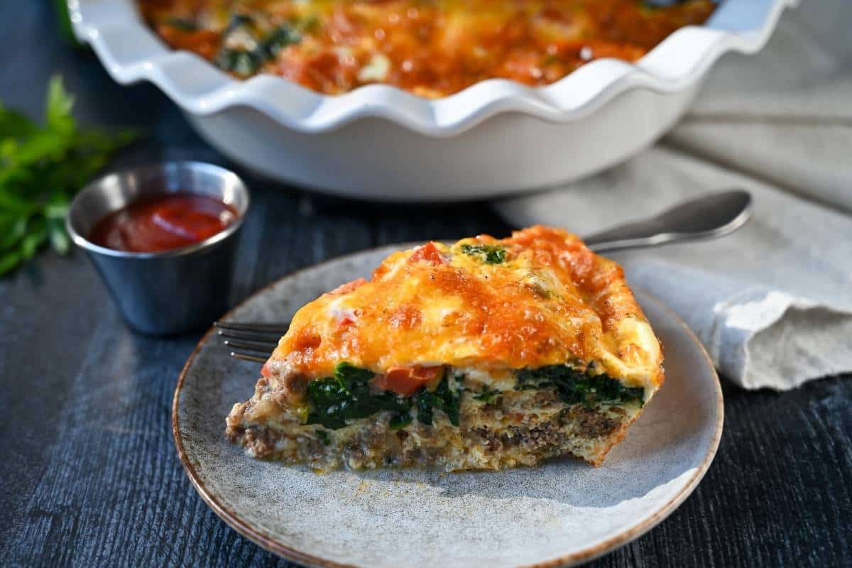 a photo of a slice of cheeseburger quiche on a plate with a fork