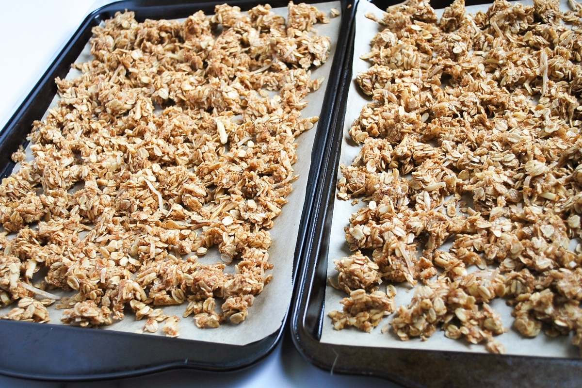 granola mixture spread onto sheet pans ready to bake