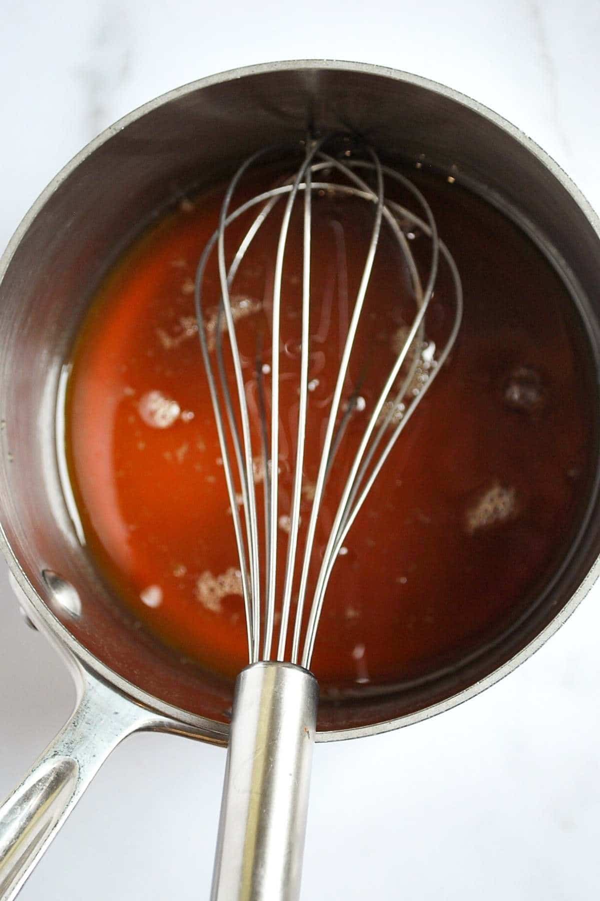 wet ingredients for vanilla almond granola in a saucepan with a whisk