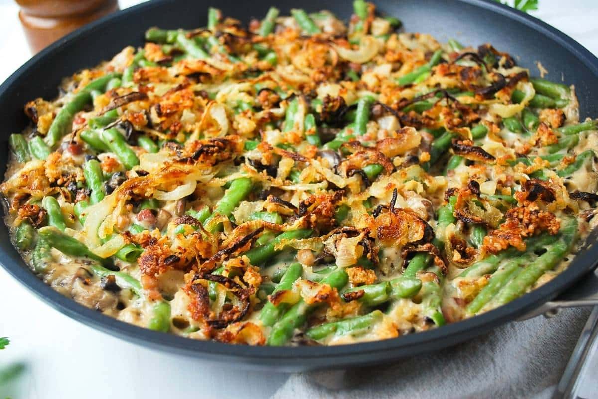 side view of a skillet with green bean casserole topped with crispy onions