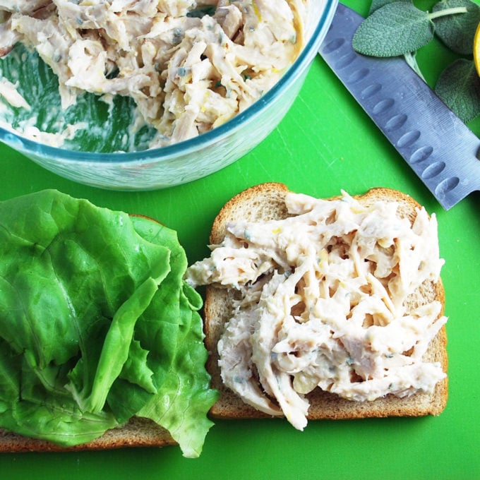overhead photo of an open-faced chicken salad sandwich with butter lettuce and bowl of chicken salad
