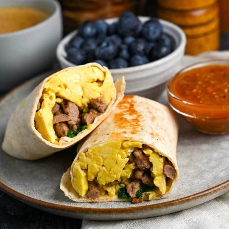 a sliced turkey sausage and egg burrito on a plate with sides