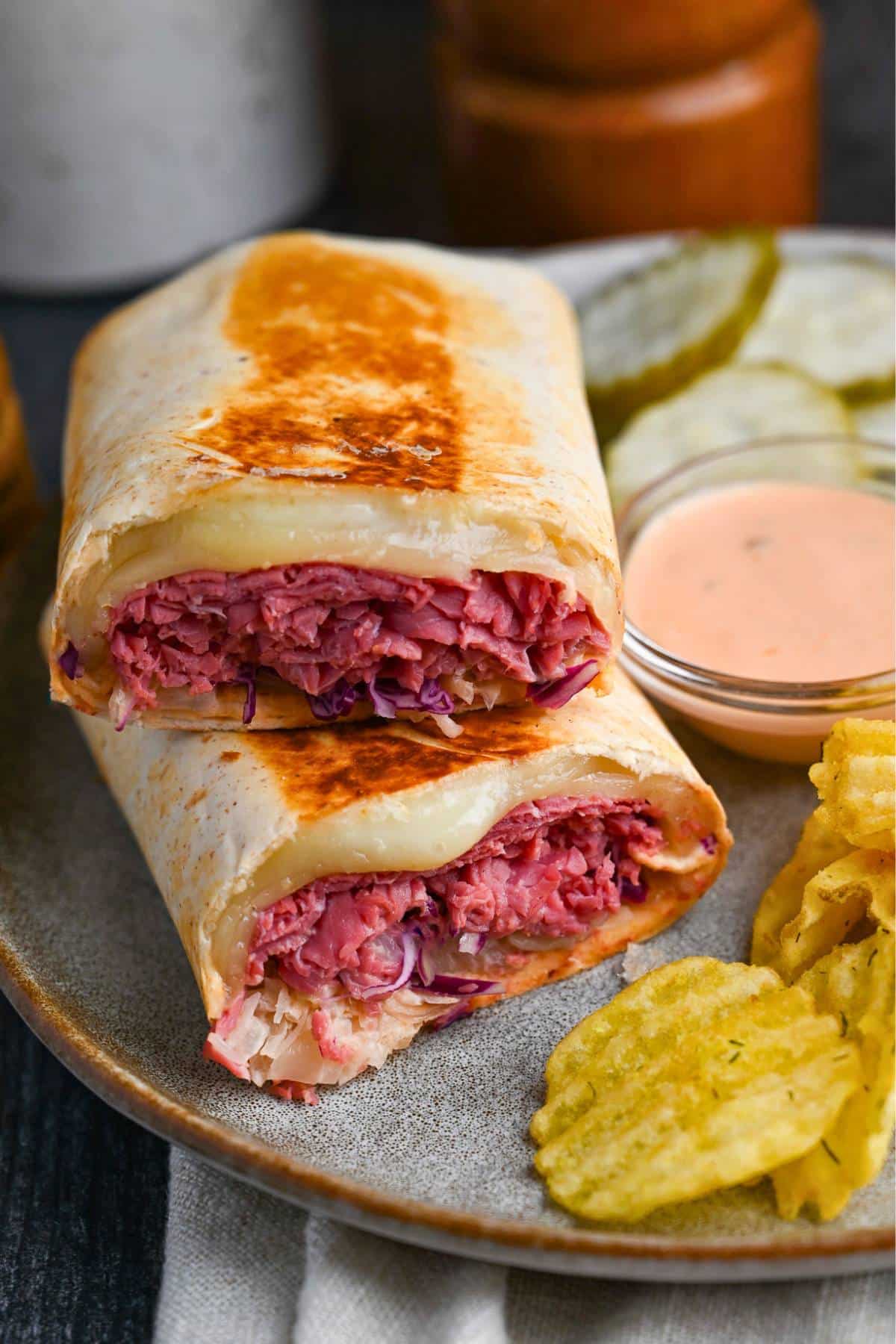 a stacked reuben sandwich on a plate with chips