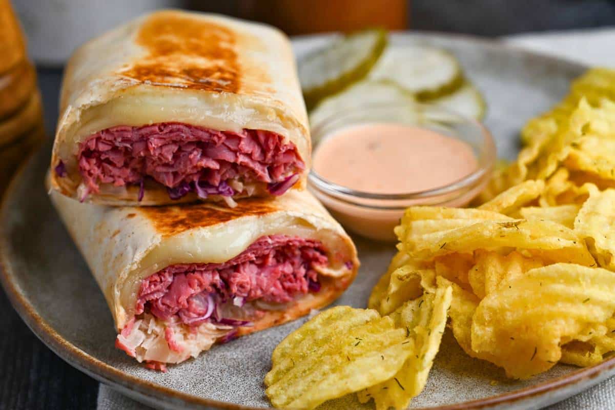 a wrap on a plate with chips and pickles
