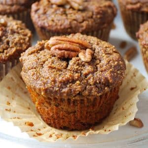close up of a pumpkin muffin topped with chopped pecans in a peeled back cupcake wrapper
