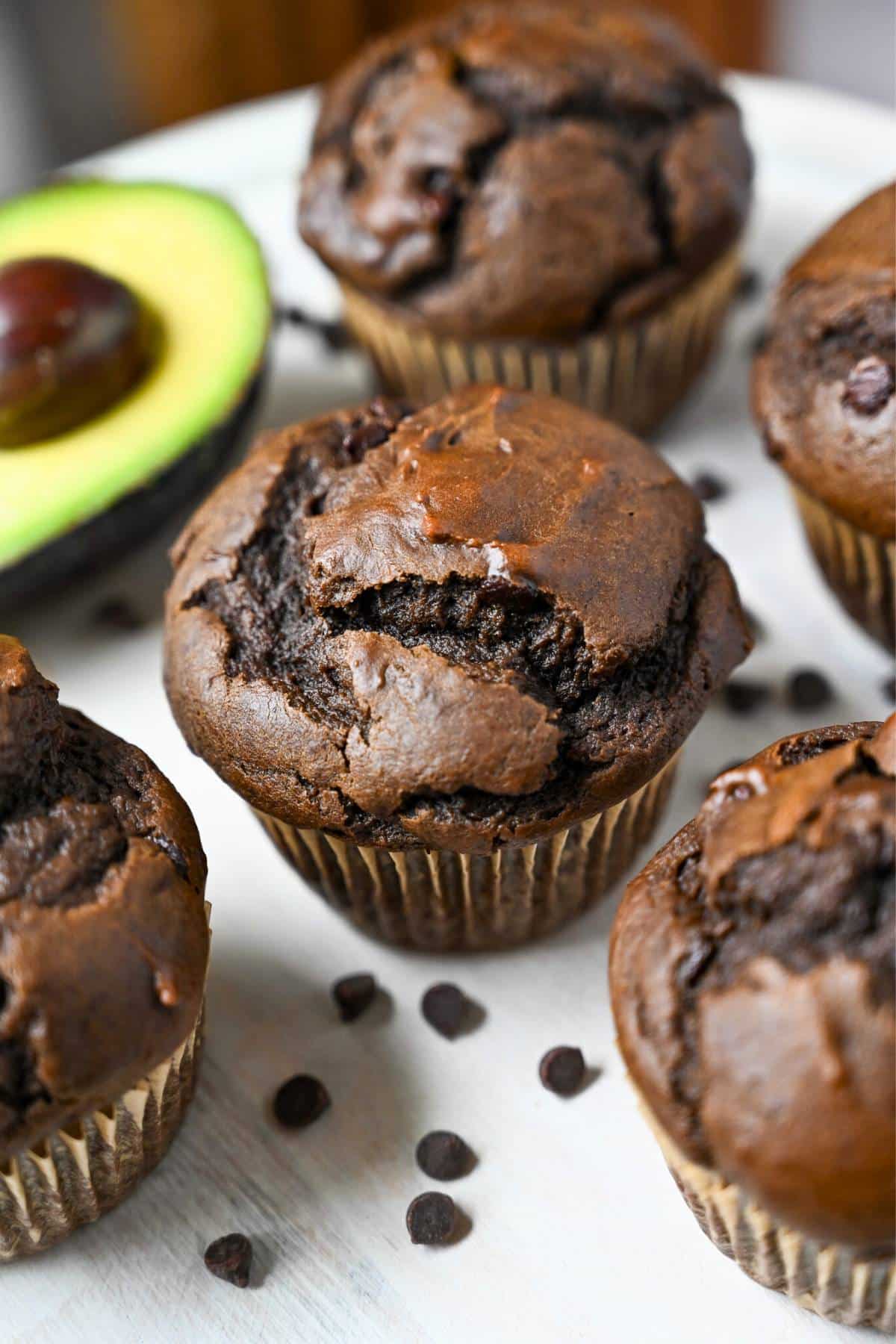chocolate muffins with chocolate chips on a platter with a half avocado sliced