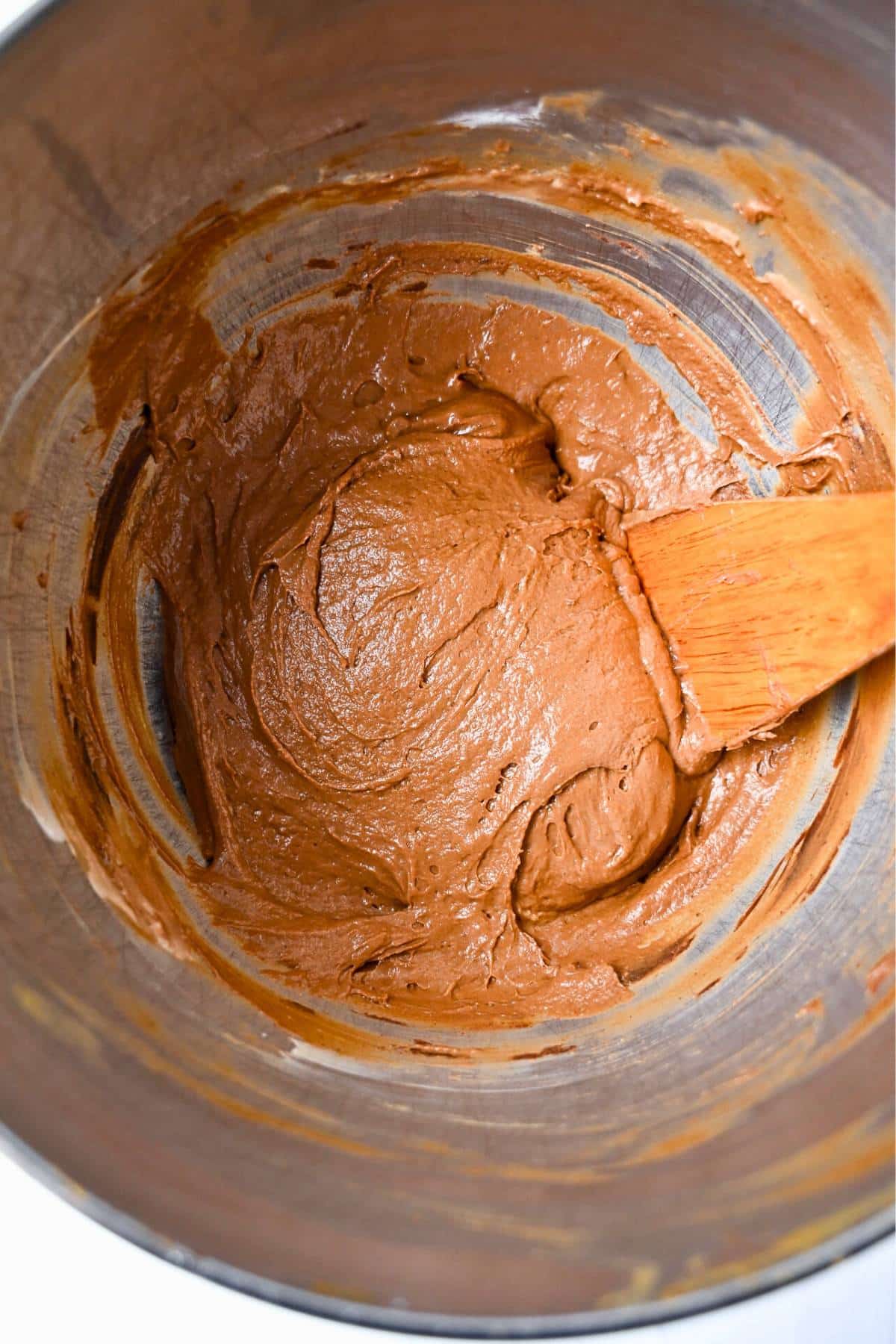 chocolate muffin batter in a bowl with a wooden spoon