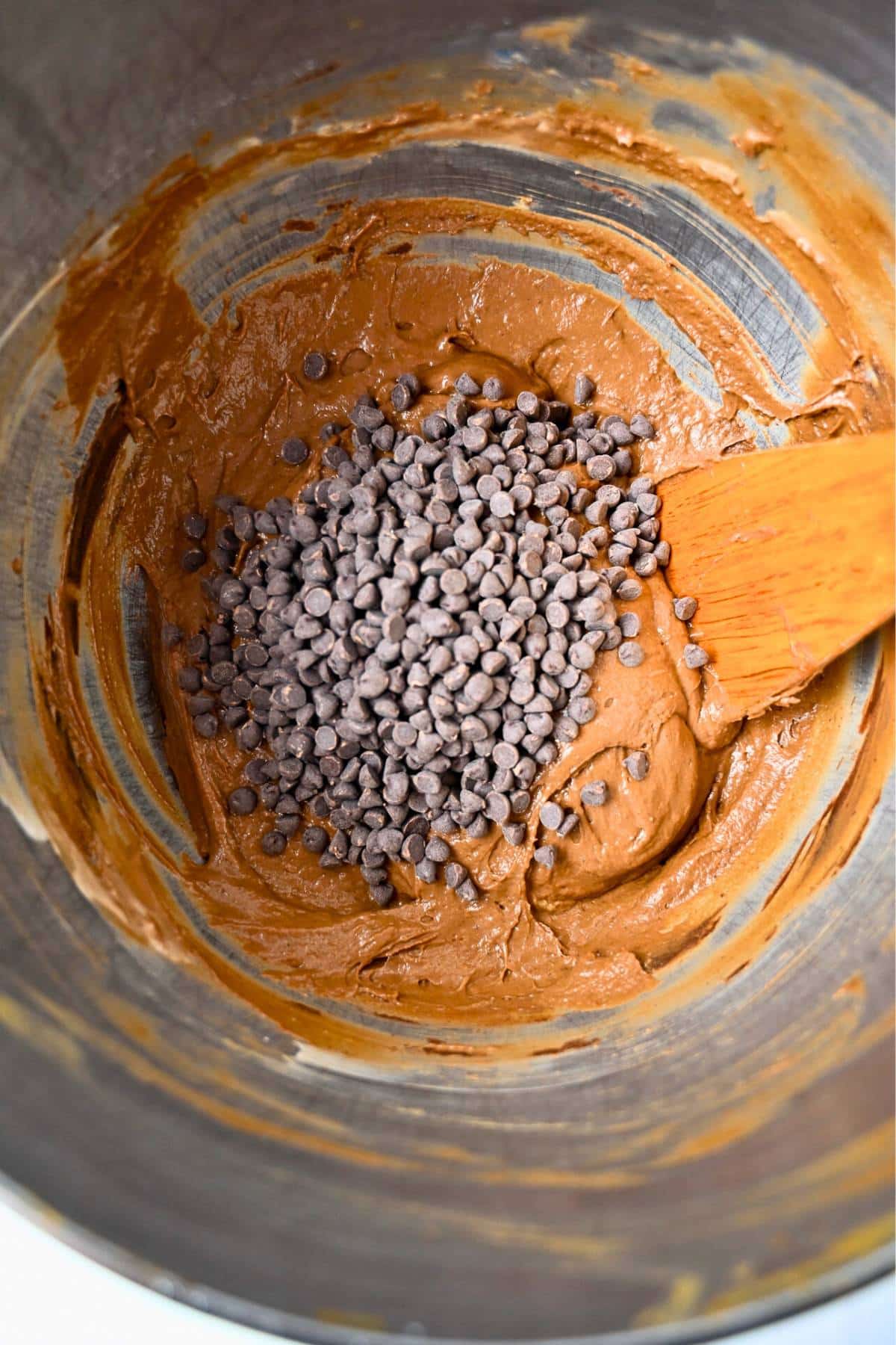 chocolate chips on top of muffin batter with a spoon