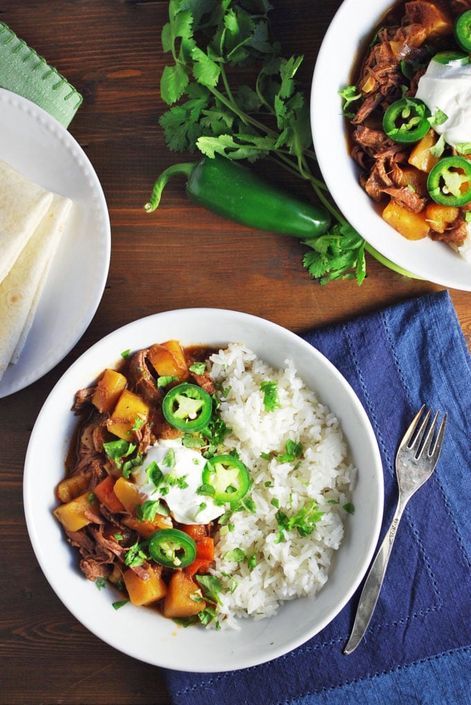 two bowls of Mexican picadillo with a blue napkin and fork