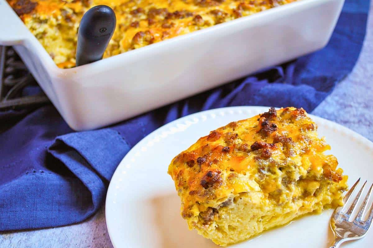 a sliced serving of a sausage egg and cheese casserole on a plate with a fork