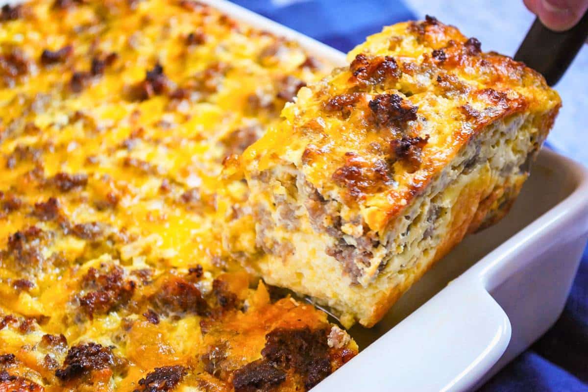 holding up a slice of a custard sausage and cheese casserole