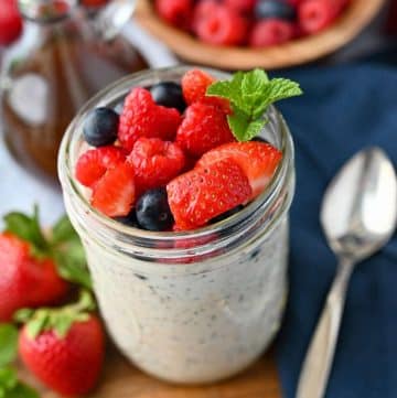 close up of a jar of protein oats topped with berries and a napkin and spoon