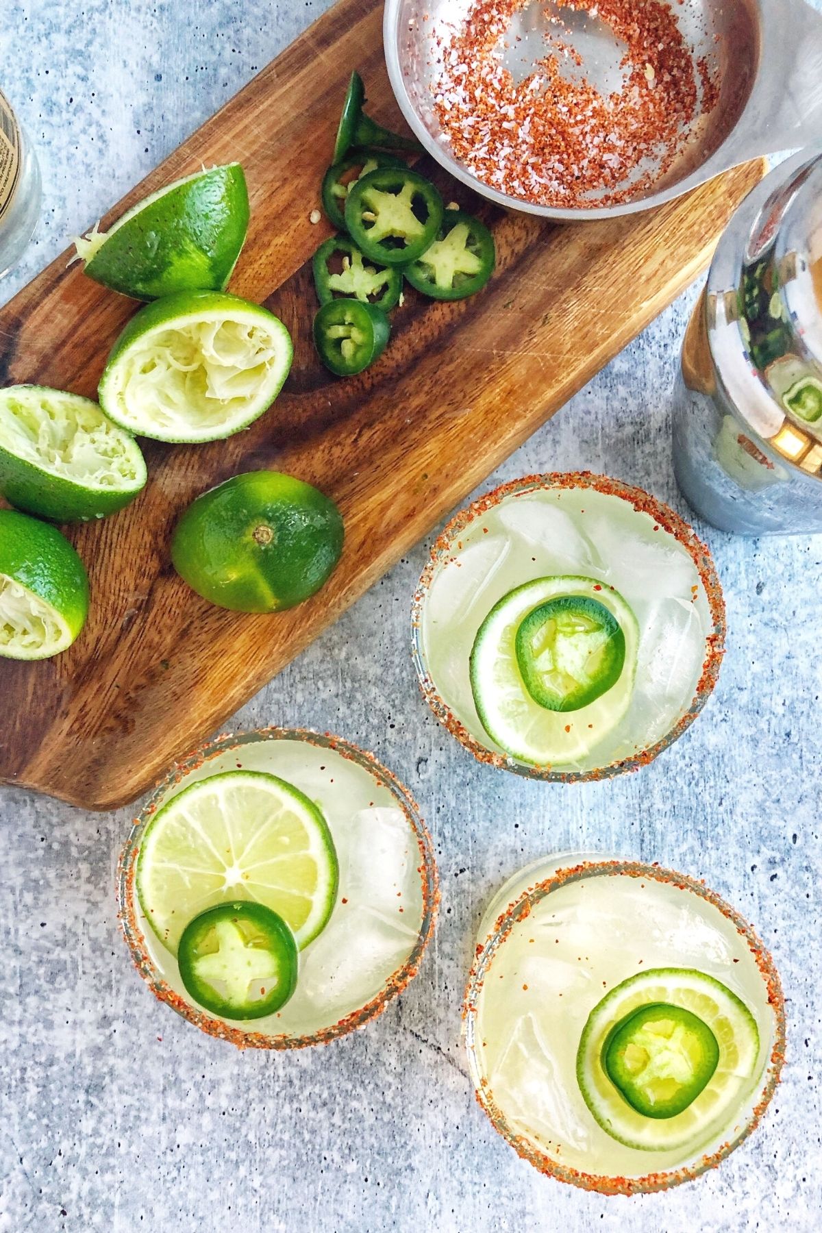 overhead photo of margaritas with fresh limes and seasoned salt on a cutting board