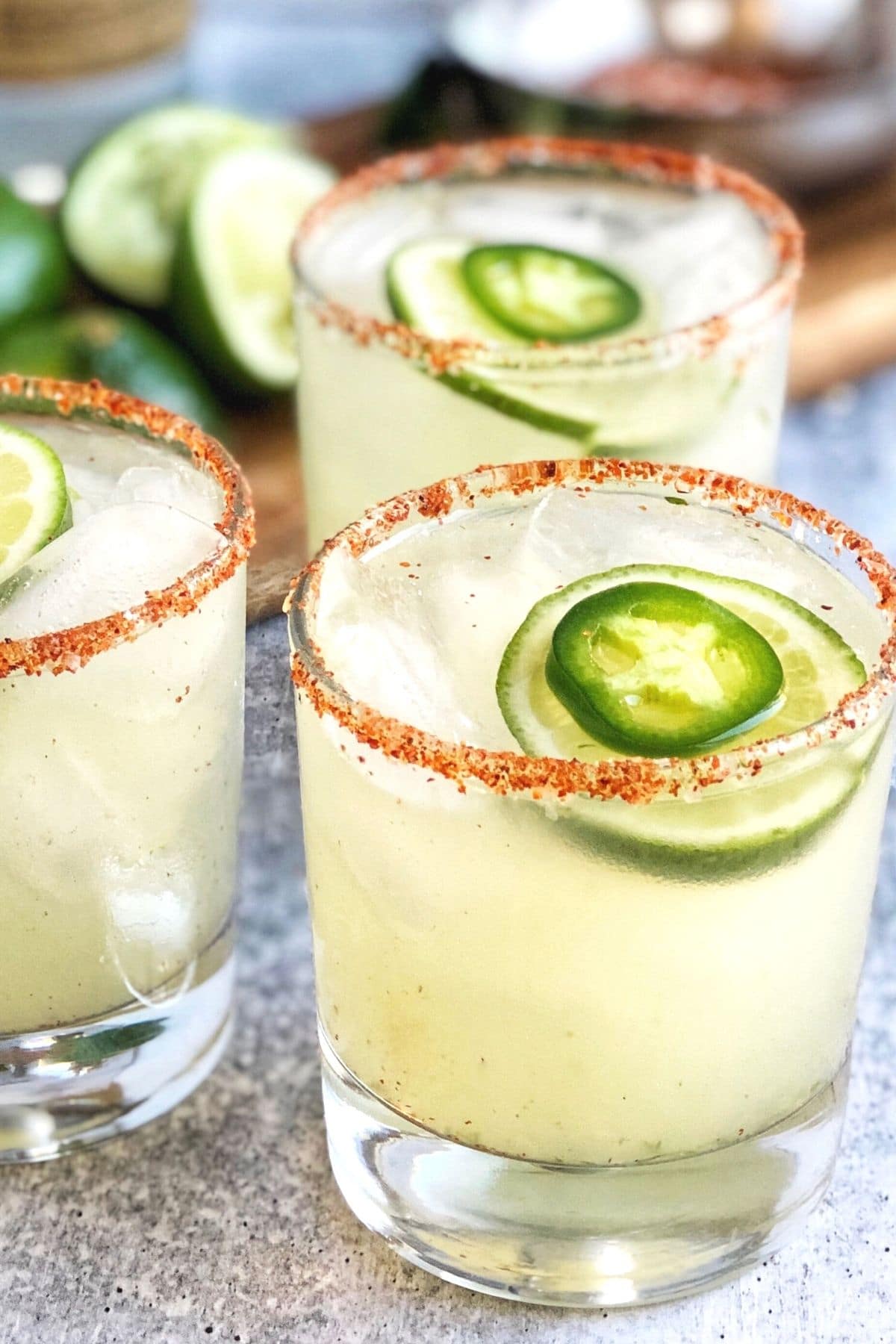 3 skinny spicy margaritas in low ball glasses with a smokey rim and fresh jalapenos and lime