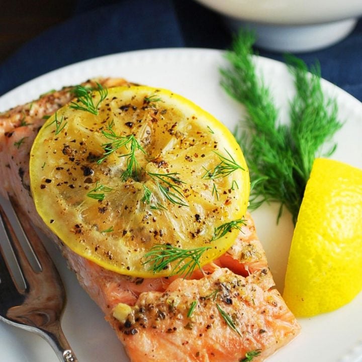 plate of salmon with a lemon wedge and herbs