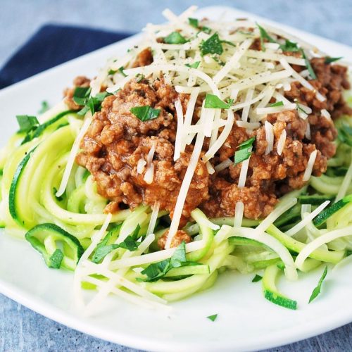 plate of zucchini noodles topped with bolognese sauce and cheese