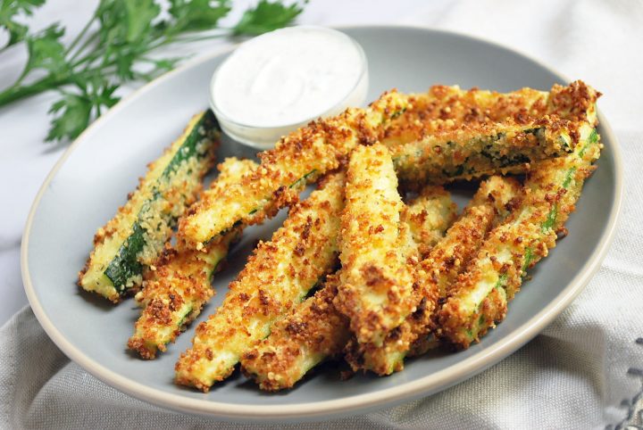 zucchini fries with dipping sauce on a plate with parsley