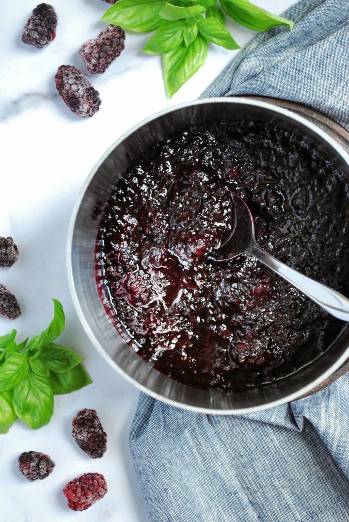 pot of compote with napkin underneath and berries in the background