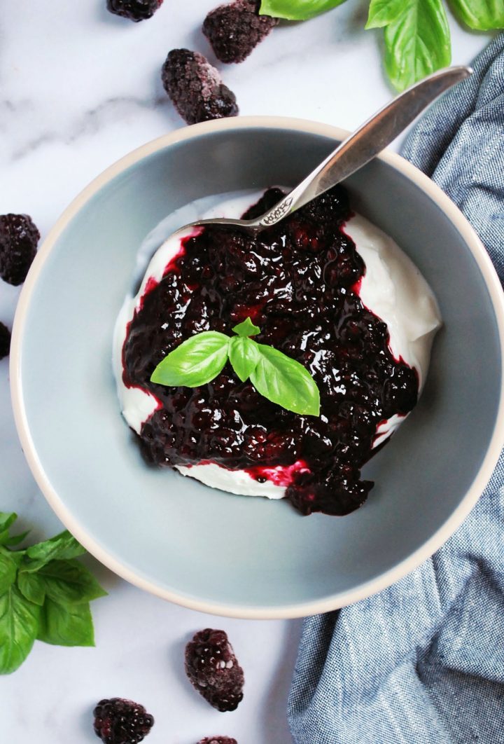 bowl of Greek yogurt with blackberry compote and fresh basil on top
