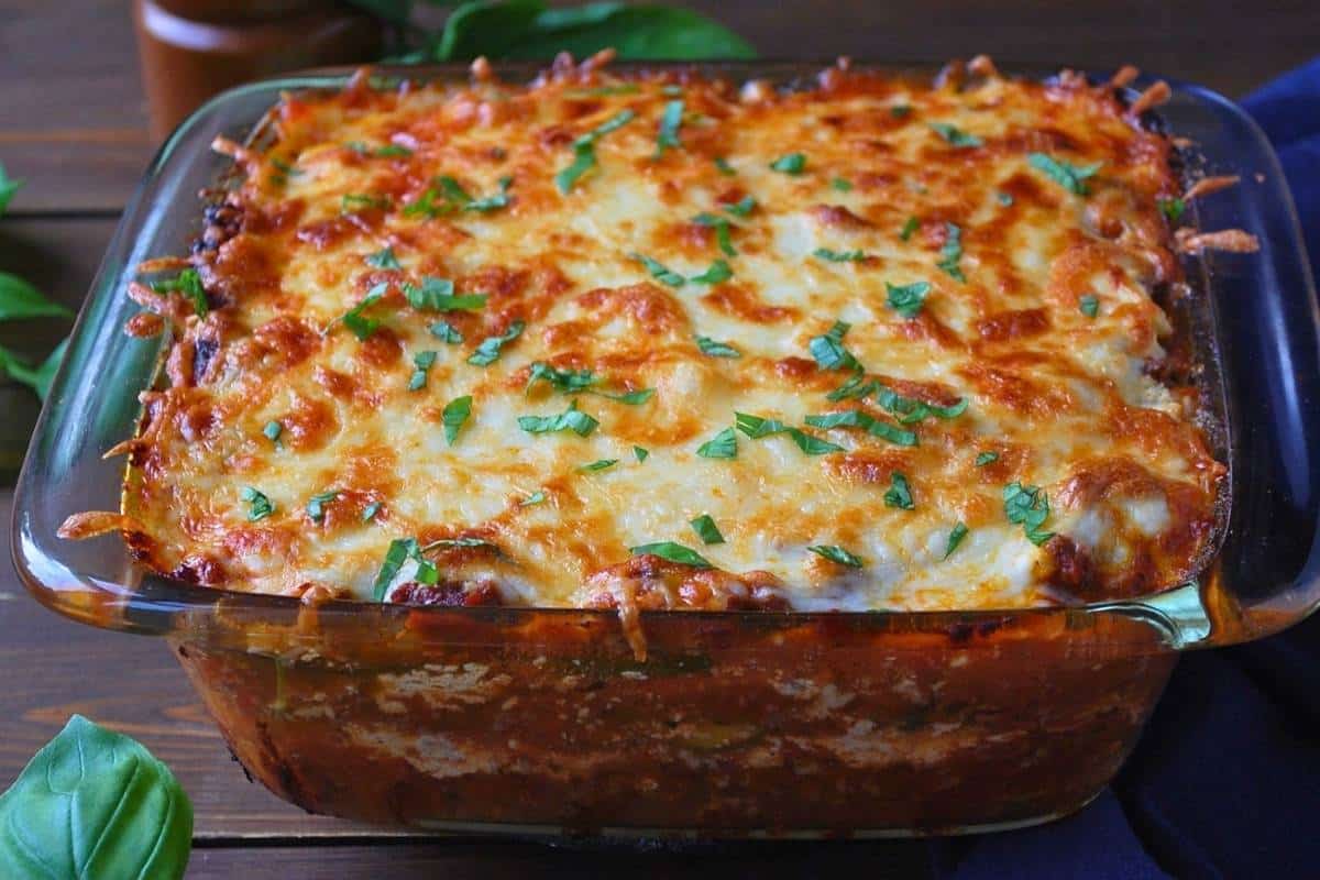 close up of a cooked pan of zucchini lasagna with fresh basil sprinkled on top