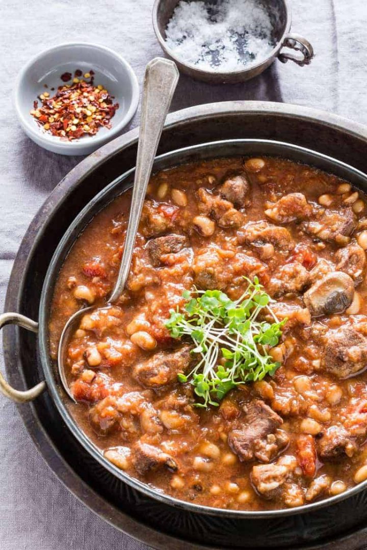 pan of bean venison stew with microgreens on top