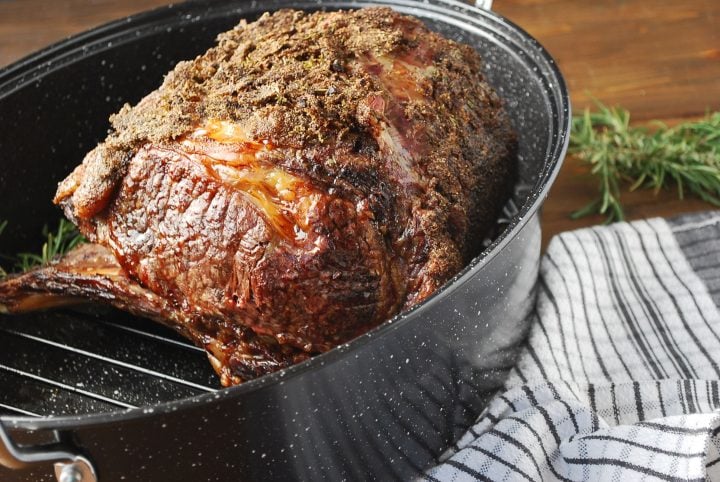 cooked standing rib roast resting in a roasting pan