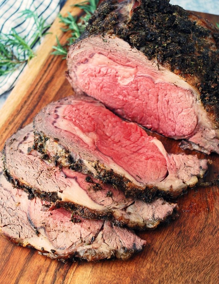 sliced standing rib roast with fresh rosemary in background