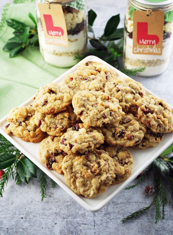 Cranberry white chocolate chip cookies on a white platter with cookie mix in jars in background