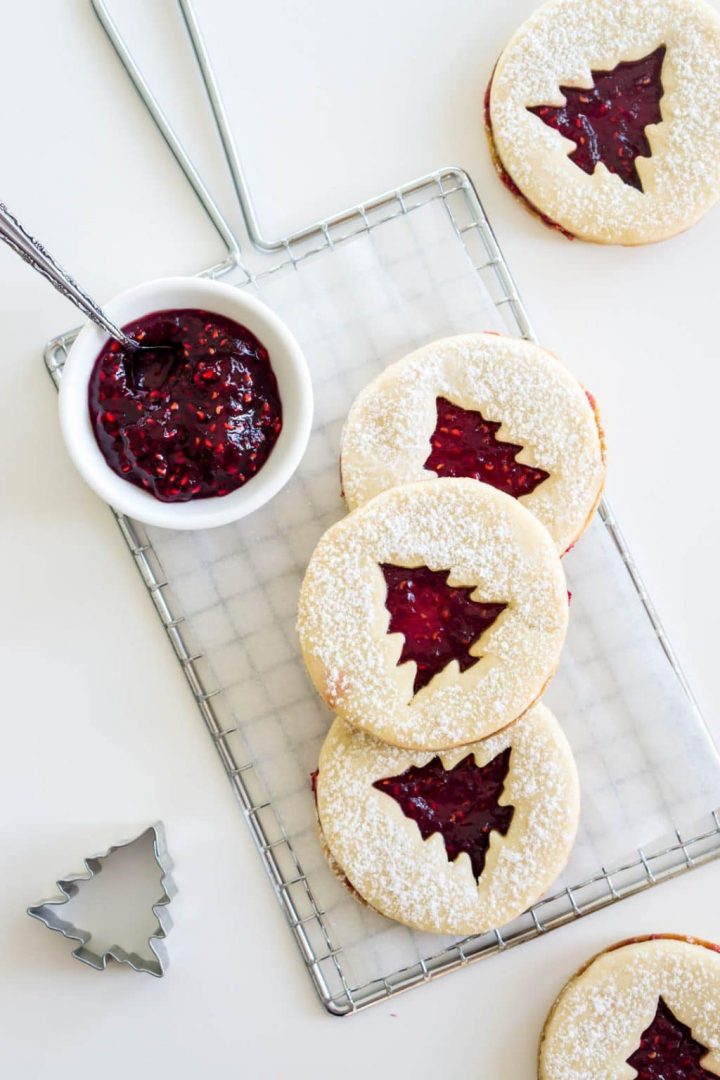 raspberry linzer cookies on a cookie rack with jam on the side