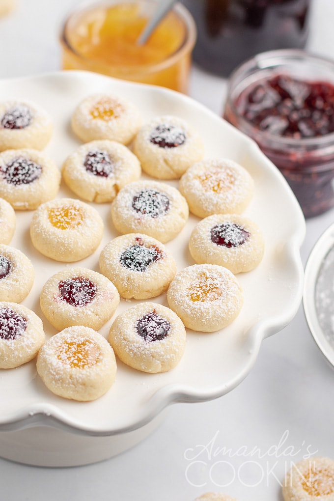 jam filled thumbprint cookies on a platter with jam in background