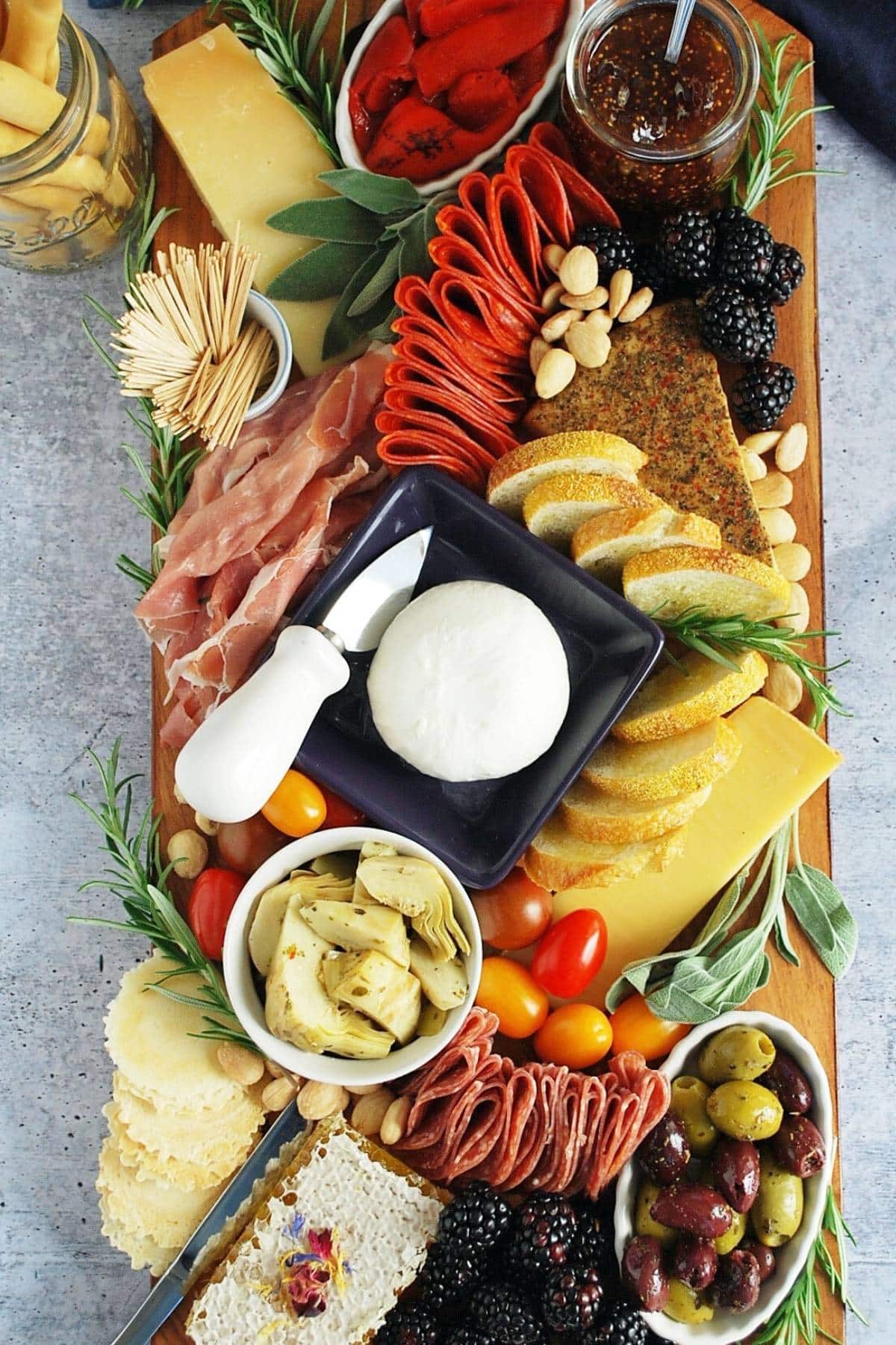 overhead photo of a charcuterie board with Italian meats, cheeses, fruit, vegetables and garnishes