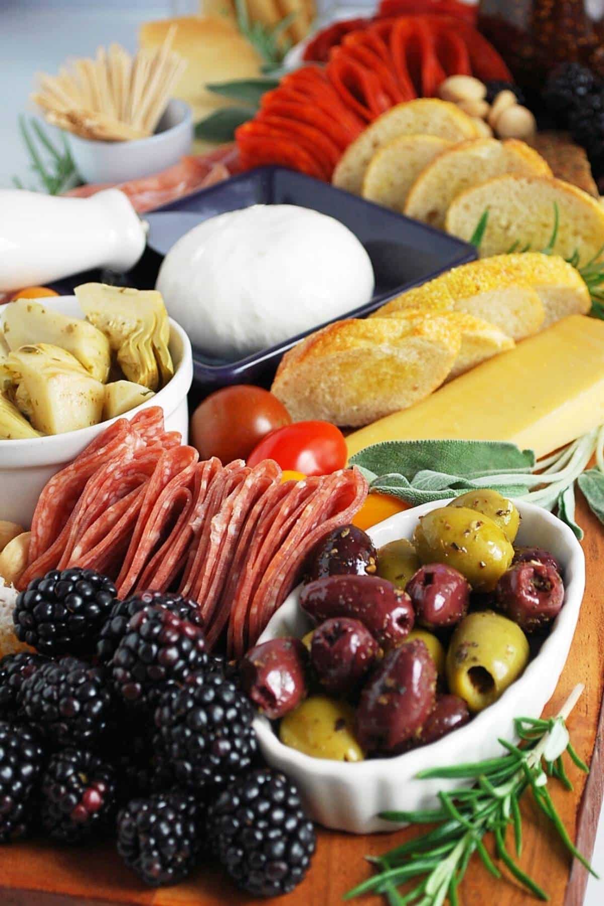 side view of an Italian charcuterie board with meats, berries, olives, cheese, and garnishes