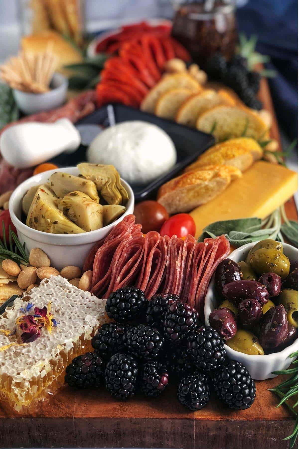 full view of an italian charcuterie board with burrata, meats, cheeses, vegetables, olives, berries, and a honeycomb