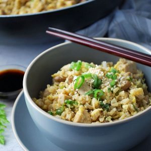 Close up of a bowl of fried rice with chopsticks laying on top