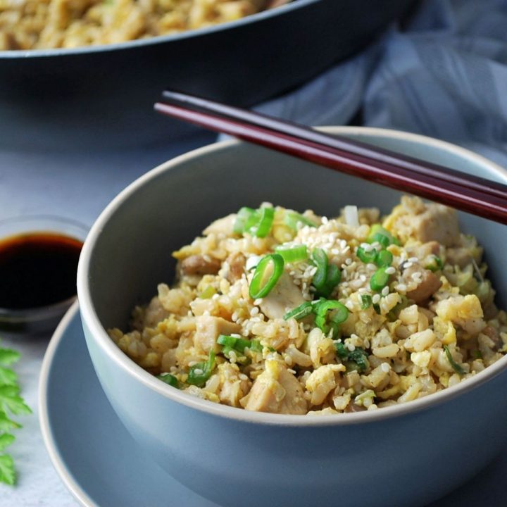 Close up of a bowl of fried rice with chopsticks laying on top