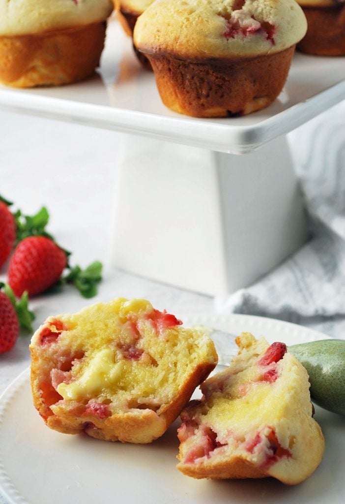 close up photo of a plate with a sliced buttered muffin on top with a butter knife