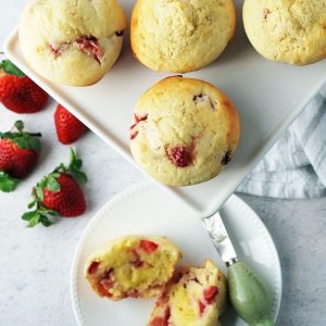 overhead photo of a platter of muffins with whole strawberries and a sliced muffin in the background