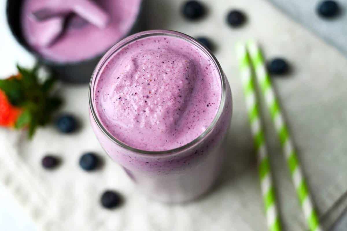 a berry bliss smoothie with straws and berries around it