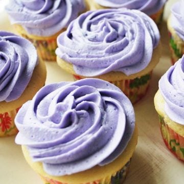 close up of a plate of cupcakes topped with lavender swirled frosting