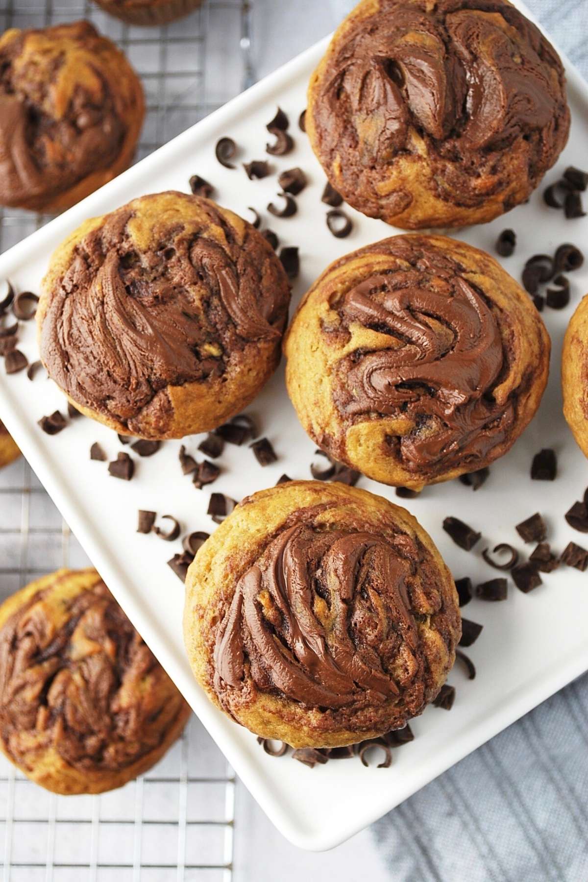 overhead photo of banana nutella muffins on a platter with chocolate shavings