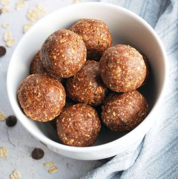 close up of chocolate protein date balls in a white bowl