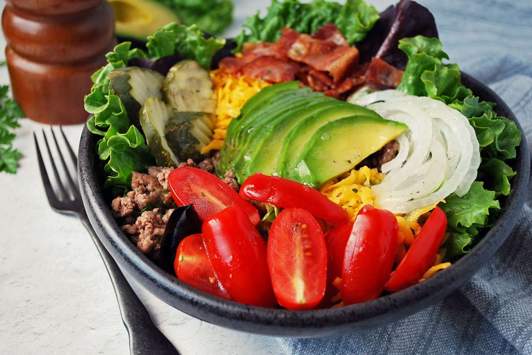 side view of California burger bowl with all the toppings and a fork on the side