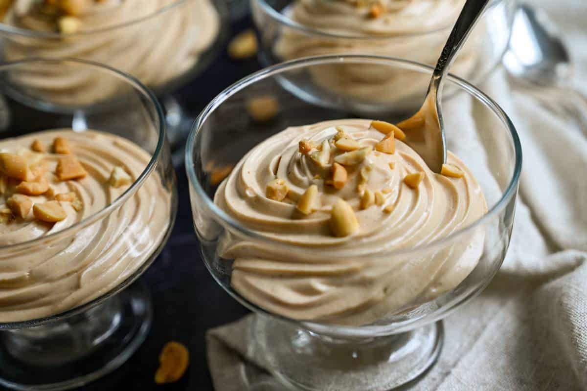 peanut butter mousse in dessert glasses with a spoon dipped in