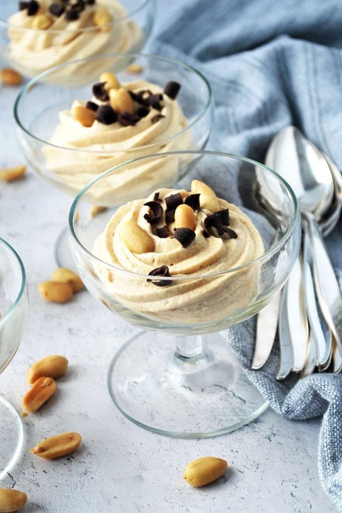 mousse topped with peanuts and chocolate in parfait dishes with spoons on the side