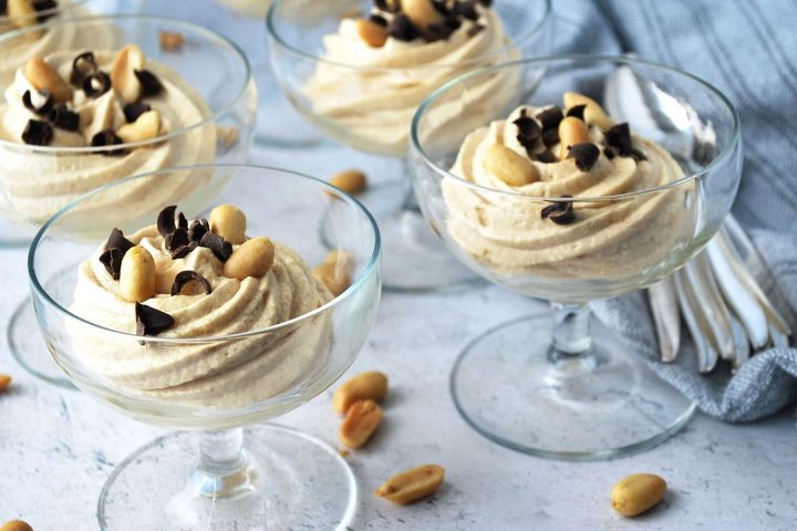 four parfait glasses filled with peanut butter mousse and toppings