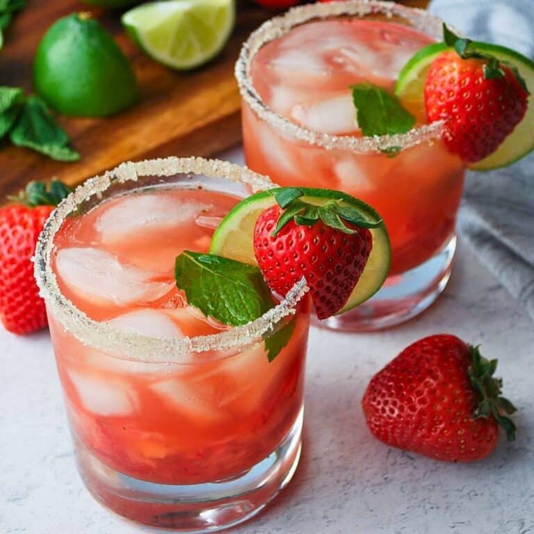 two fresh strawberry mojitos with sugar, lime, mint and a berry on the rim